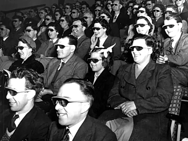 A cinema audience watching a film while wearing 3D glasses.