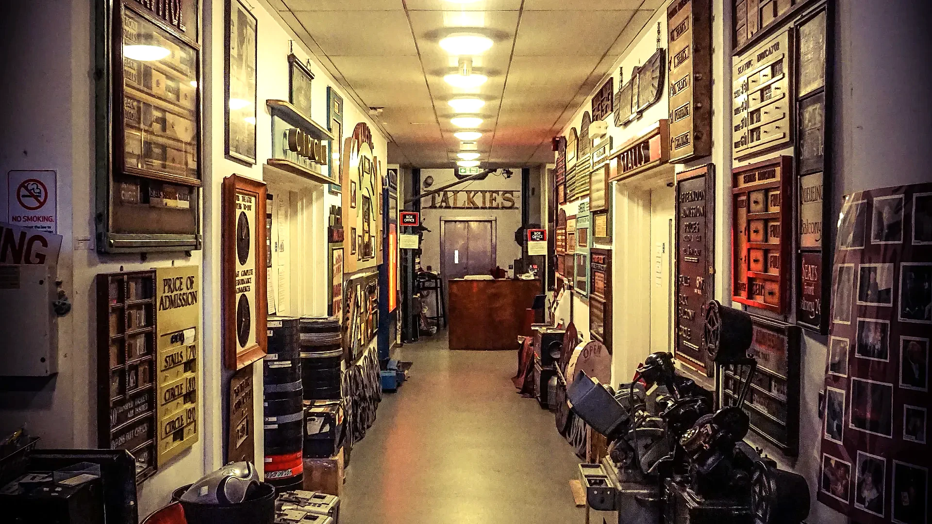 A view down the main entrance hall of the Cinema Museum. The walls are lined with many vintage signs and other artefacts.