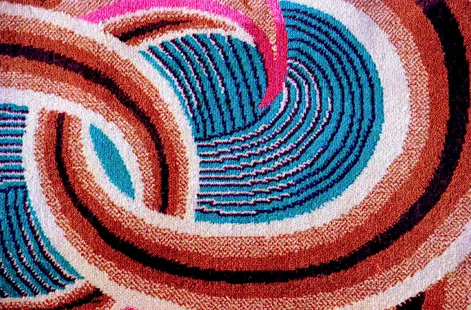 A section of carpet showing an elegant swirling 1930s pattern in blue and brown.