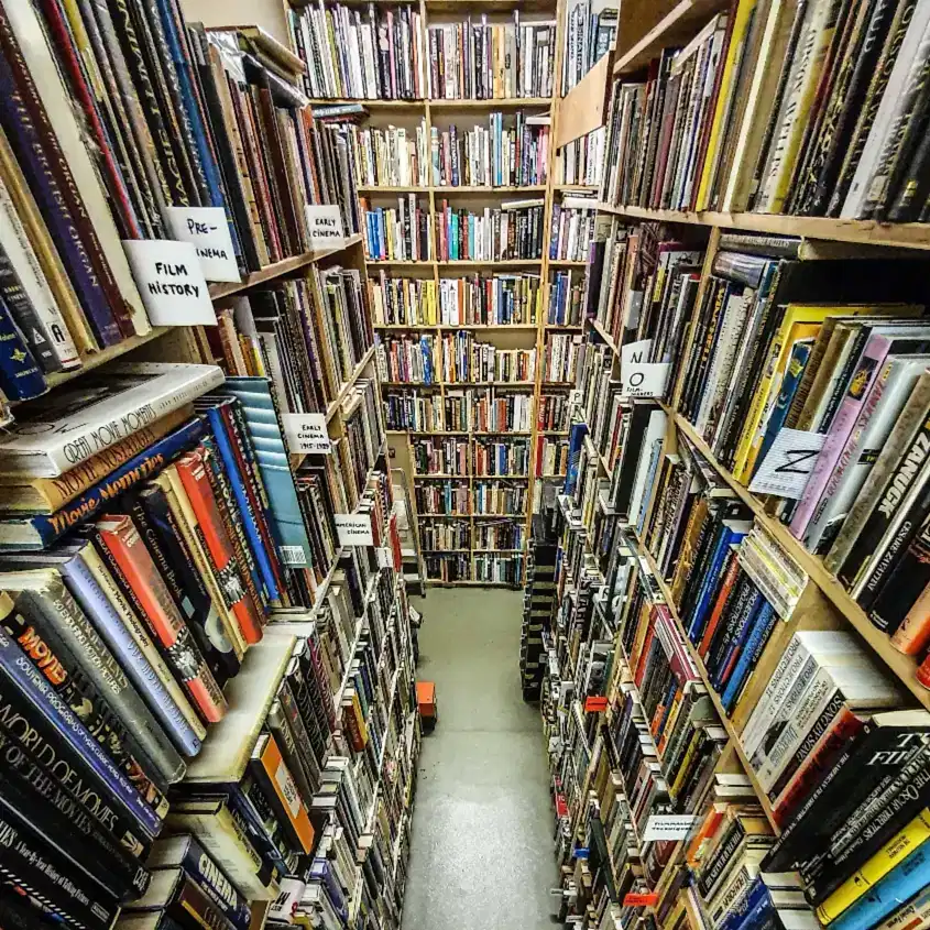 A view of three bookcases crammed with books on subjects related to cinema. The shelves have labels sticking out and identifying various subjects.